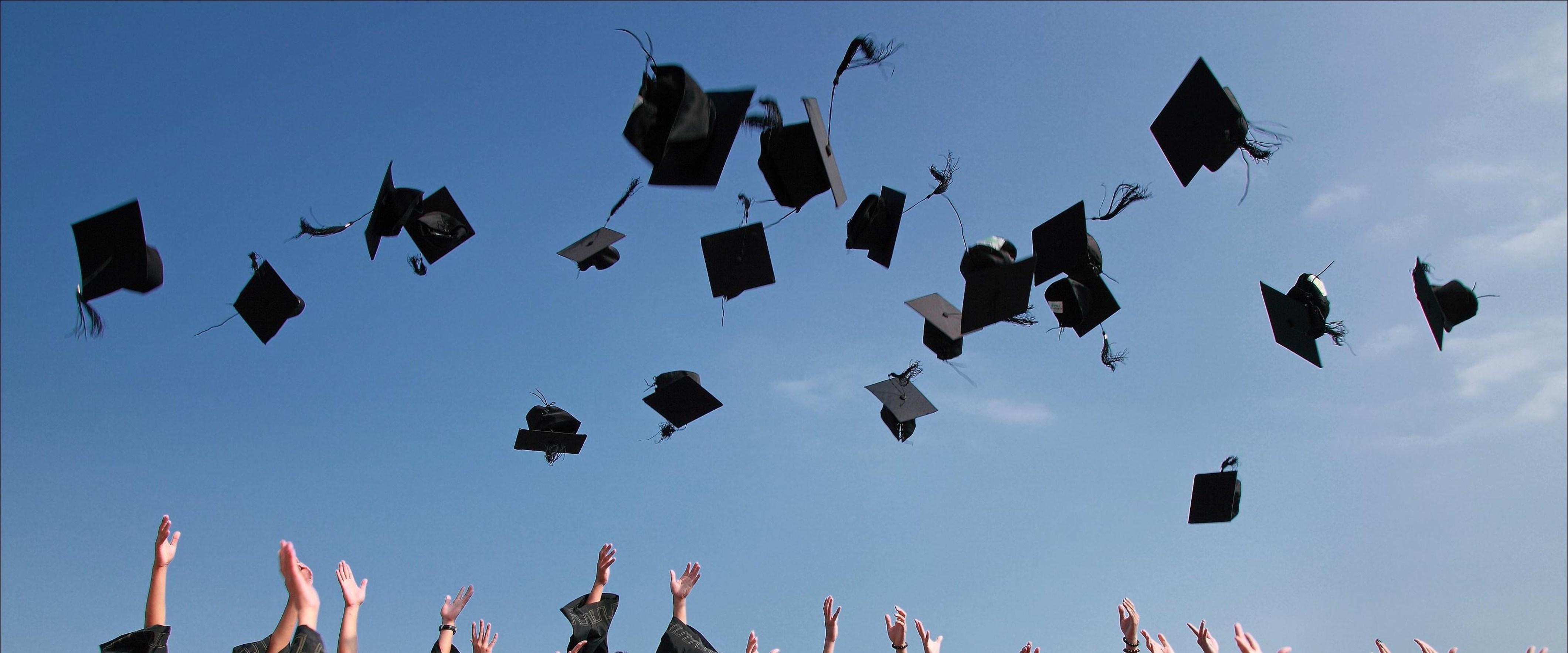 Graduates throwing mortar boards in the air